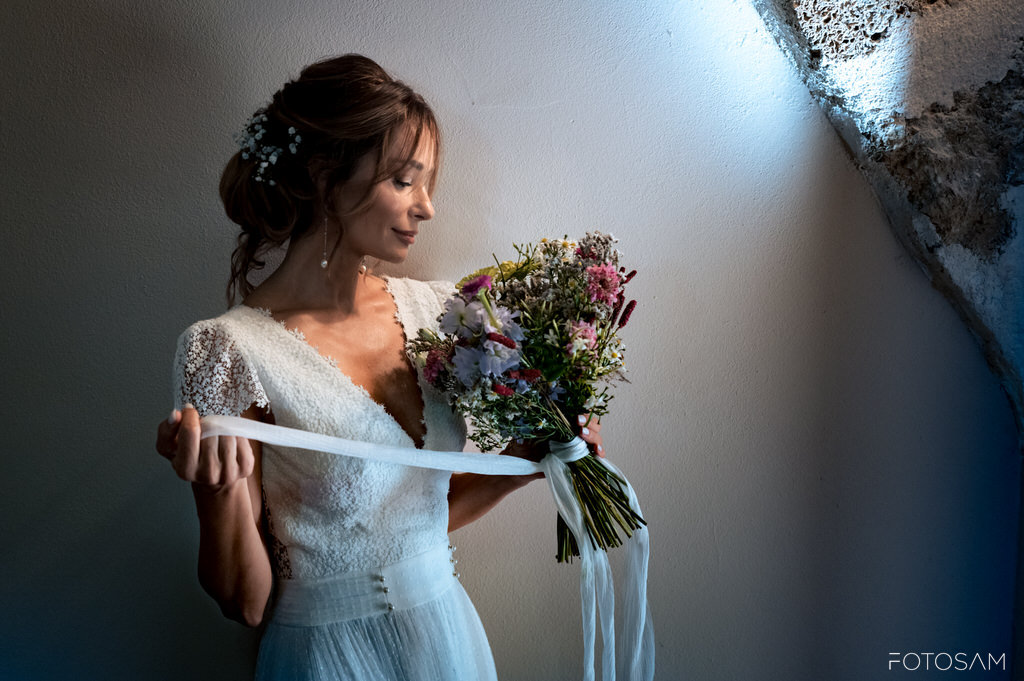 Romantico raggio di sole che illumina la sposa con il suo variopinto bouquet di fiori di campo
