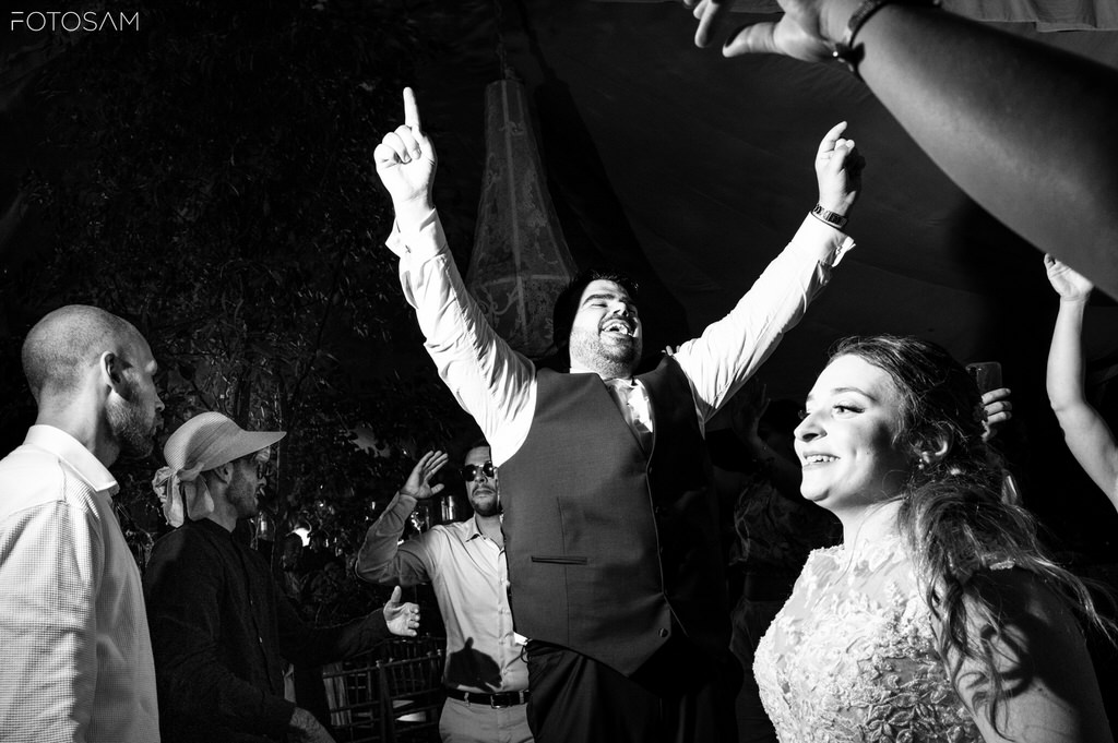 sposi e amici che ballano e ridono insieme nella festa serale