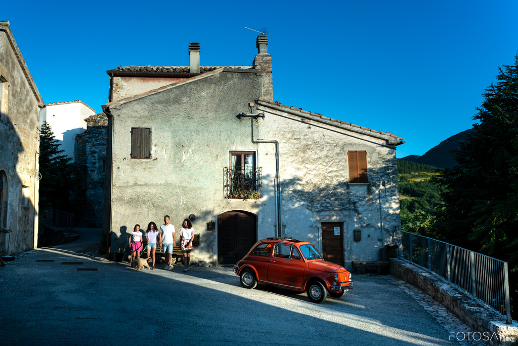 famiglia-in-passeggiata-davanti-al-borgo-con-auto-rossa