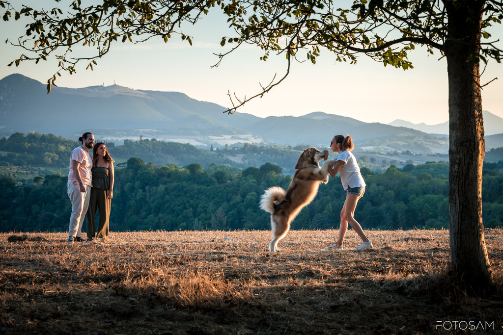 coppia-che-gioca-con-il-cane-in-un-campo-con-vista-sulle-colline