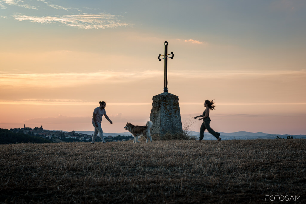 coppia-che-gioca-con-il-cane-accanto-a-un-monumento-al-tramonto