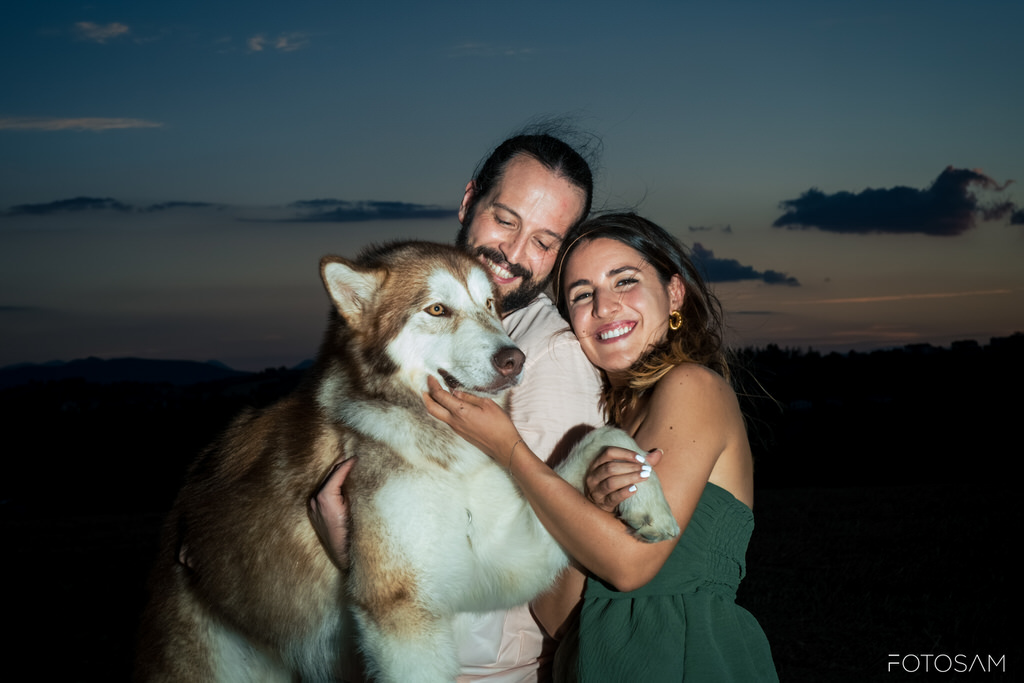 coppia-che-abbraccia-il-cane-in-primo-piano-durante-il-tramonto