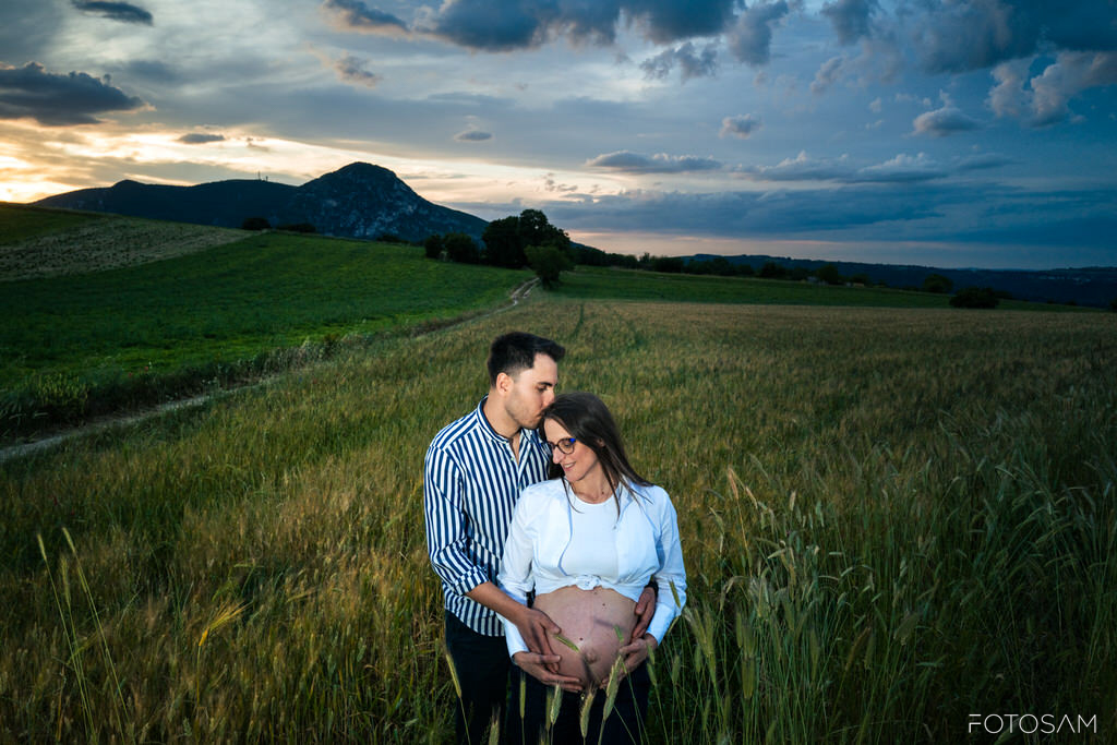 futura-mamma-e-partner-in-un-paesaggio-verde-al-tramonto
