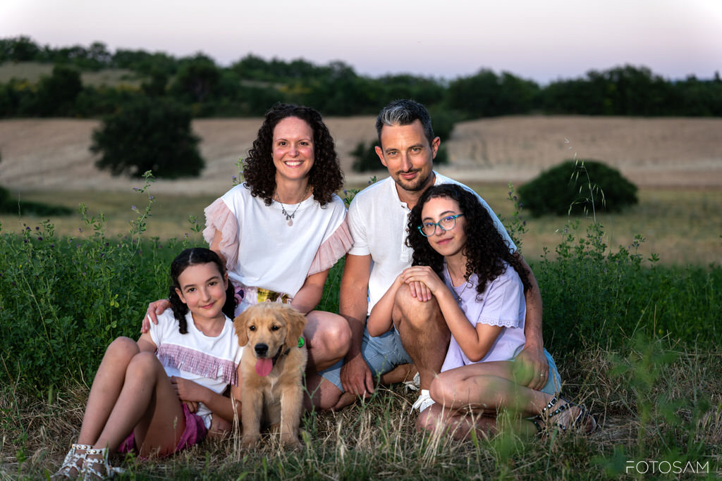 ritratto-familiare-all-aperto-tra-erba-e-colline
