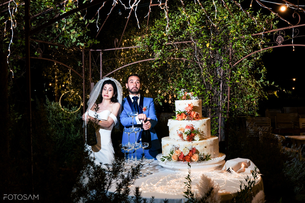 Gli sposi tagliano la torta sotto gli alberi, tra applausi e magia