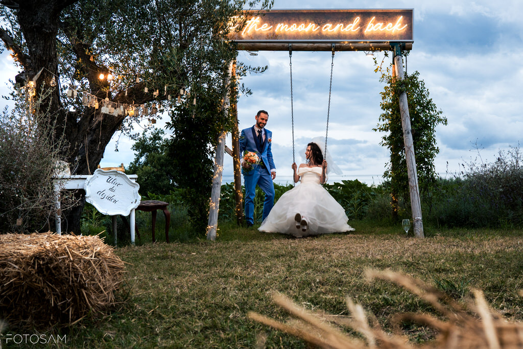 Gli sposi si scambiano uno sguardo complice sotto un'insegna romantica