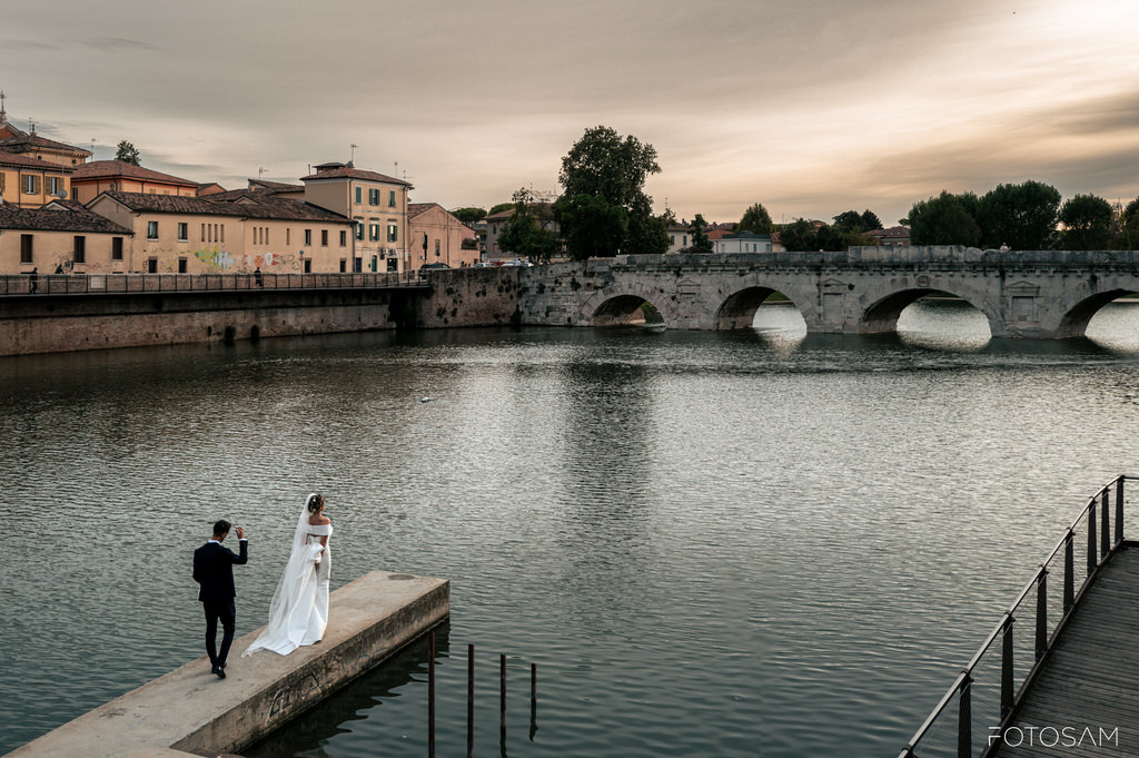 sposi-sul-pontile-con-fiume-e-ponte-sullo-sfondo-tenuta-mara
