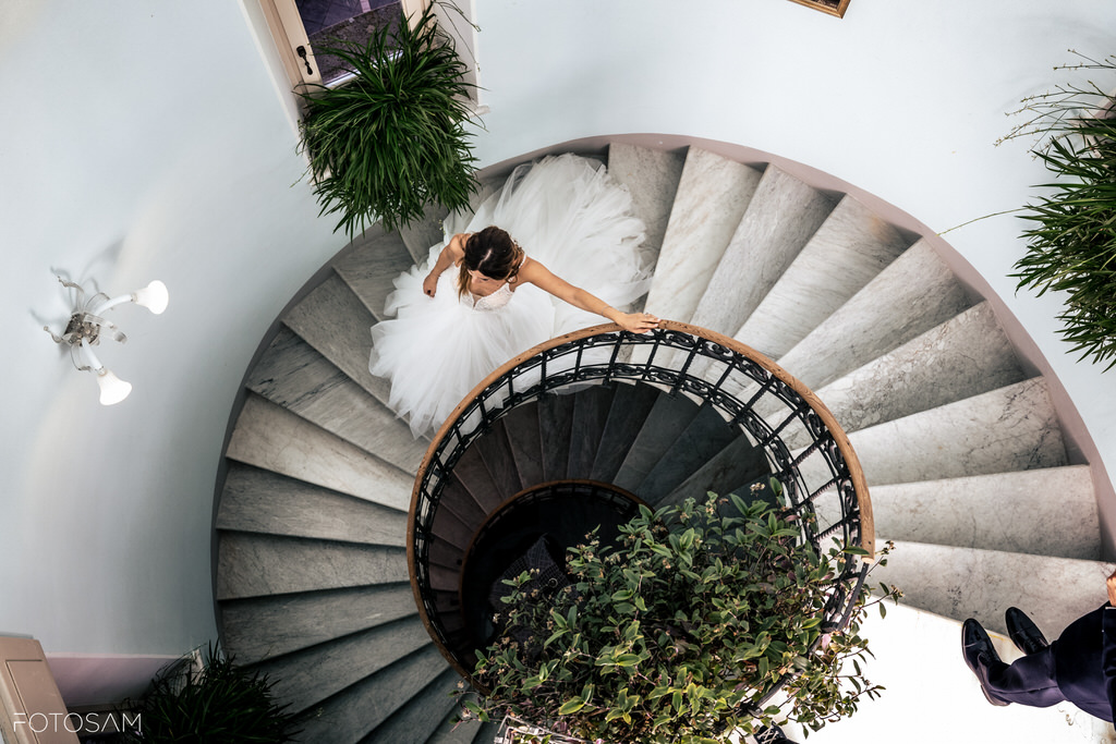 Scatto dall’alto della sposa sulla scala a chiocciola, dettaglio architettonico di grande impatto