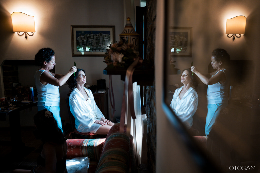 a-sposa-si-prepara-nella-stanza-del-castello-con-lo-specchio-che-riflette-lintimita-del-momento-luce-naturale-e-dettagli-degli-accessori