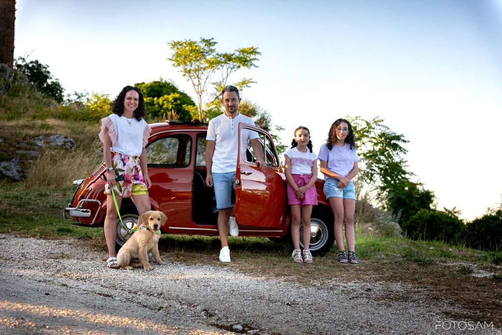 famiglia-posata-all-aperto-con-cane-e-auto-vintage