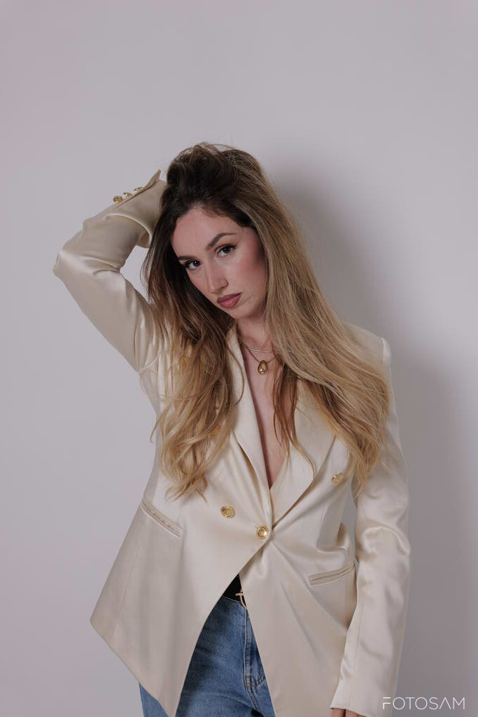 donna-con-blazer-bianco-in-posa-con-una-mano-tra-i-capelli