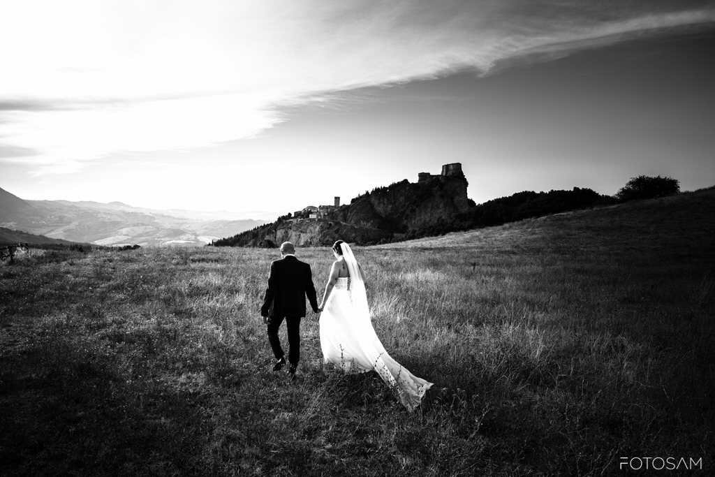 sposa-con-il-velo-al-vento-e-sposo-nel-paesaggio-di-san-leo