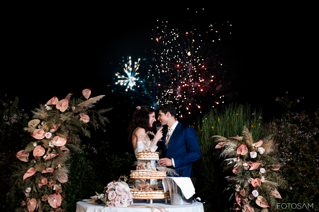 gli-sposi-tagliano-la-torta-allaperto-circondati-da-decorazioni-floreali-e-illuminazione-soffusa